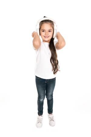 smiling little girl listening music in headphones isolated on whiteの写真素材