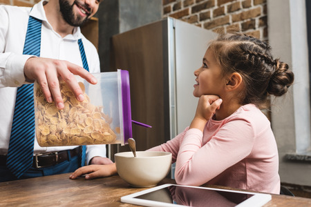 father making cereal breakfast for daughter while they preparing for work and school