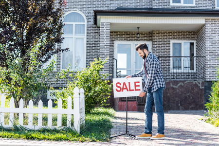young man with sale board selling his houseの写真素材