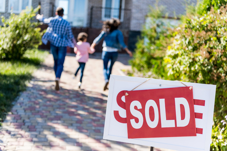 family running to new house with sold signboard on foregroundの写真素材