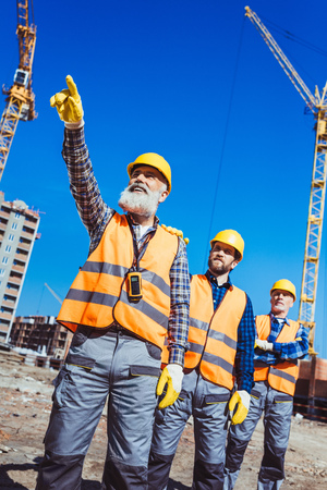 Foreman pointing his finger and showing something to other workers at construction site