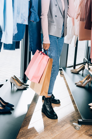 cropped shot of woman with shopping bags in clothing storeの写真素材