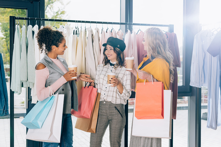 group of young women with shopping bags and coffee to go in clothing storeの写真素材