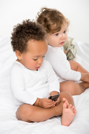 multiethnic toddlers holding money and credit cards isolated on whiteの写真素材