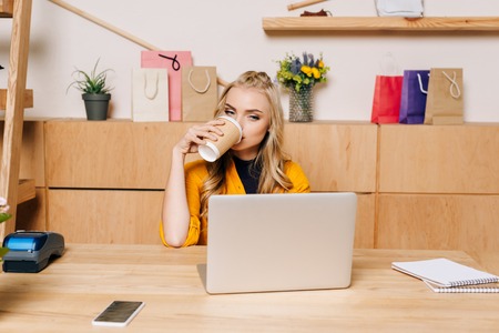 clothing store manager drinking coffee from disposable cup at workplaceの写真素材