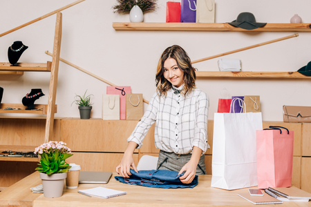 clothing store manager folding shirt to pack it into shopping bagの写真素材