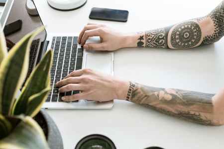 Simplistic workplace with plant, photographic lenses and man typing on laptopの写真素材