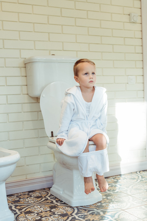 cute little boy in white underwear sitting on toilet and looking awayの写真素材