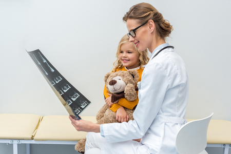 young beautiful doctor showing x-ray scans to little patientの写真素材