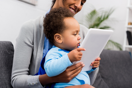 african american mother and little son with digital tablet at homeの写真素材