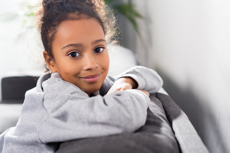 african american adorable child sitting on sofa at homeの写真素材