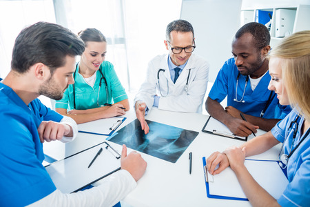 multiethnic team of doctors discussing x-ray scan of human pelvisの写真素材