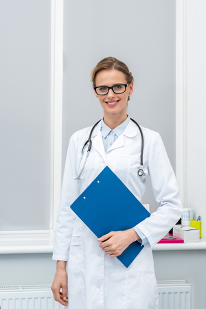 young female doctor with clipboard looking at cameraの写真素材
