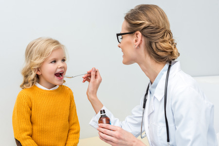 young female doctor giving syrup to little girlの写真素材