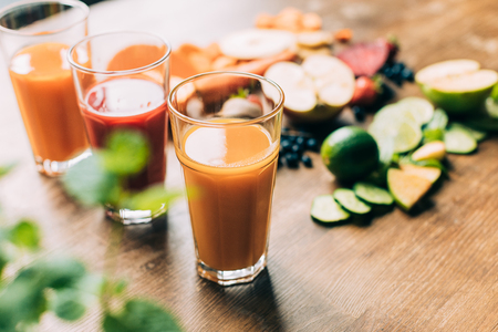 close-up view of fresh healthy fruit and vegetable smoothies in glasses on table   の写真素材
