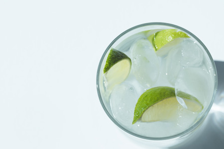 top view of Gin Tonic cocktail with lime and ice cubes in glass on whiteの写真素材