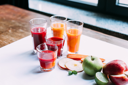 close-up view of various fruit and vegetable smoothies in glasses on tableの写真素材