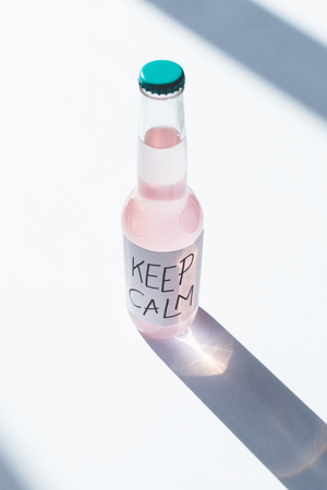 high angle view of alcoholic beverage in bottle with inscription keep calm on label on whiteの写真素材