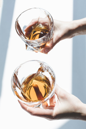 close-up partial view of person holding glasses of whiskey  の写真素材