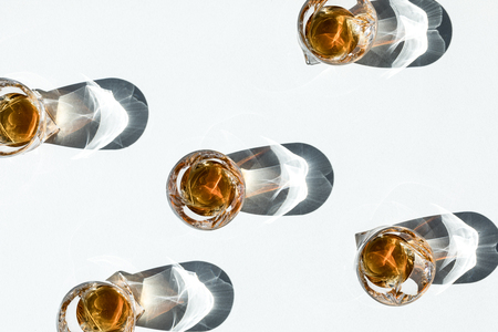 top view of luxury cool whiskey in glasses with shadows on white     の写真素材