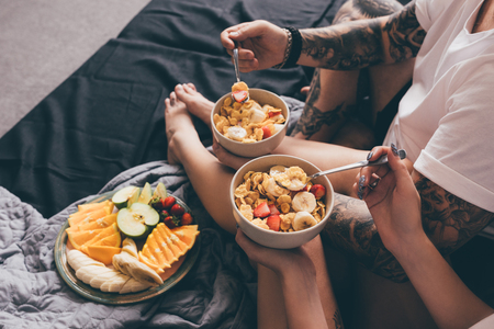 cropped shot of couple having healthy breakfast together in bed at homeの写真素材