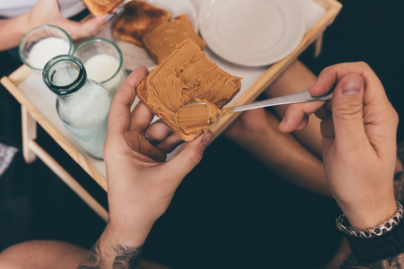 partial view of couple eating tasty homemade toasts in bed at homeの写真素材