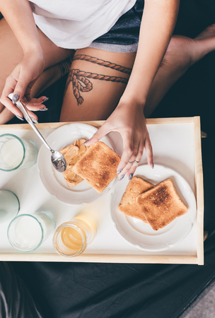 overhead view of woman eating homemade toast for breakfast in bedの写真素材