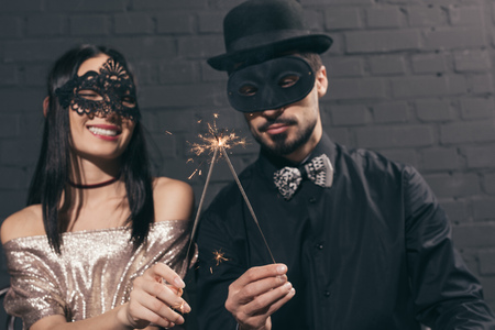 selective focus of stylish multiethnic couple in christmas masks with sparkles at new year partyの写真素材