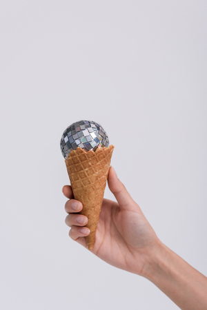 cropped shot of ice cream cone with christmas ball in hand isolated on greyの写真素材