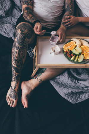 overhead view of couple having breakfast with yogurts and fruits together in bed in morningの写真素材