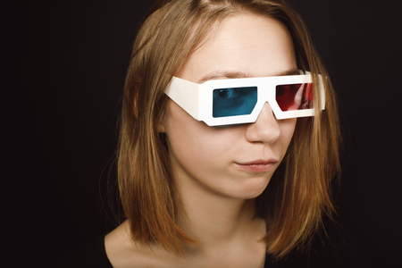close-up portrait of young woman in 3d glasses isolated on blackの写真素材