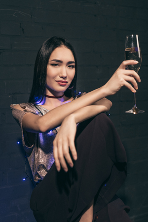portrait of attractive asian woman with glass of champagne looking at cameraの写真素材