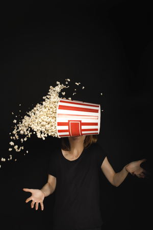 cropped shot of woman with flying bucket of popcorn isolated on blackの写真素材