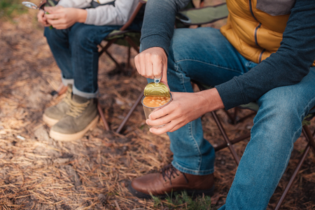 close-up partial view of father and son eating beans from can in forest の写真素材
