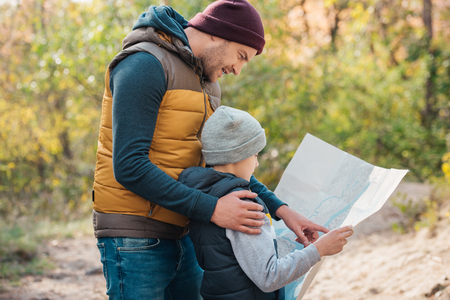 smiling father and cute little son holding map in forestの写真素材