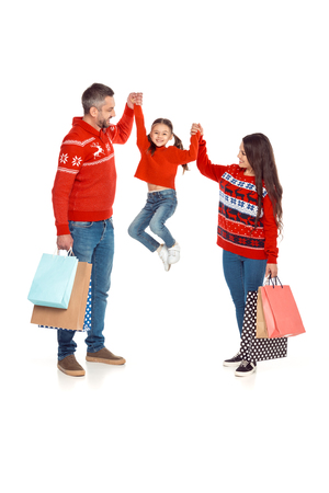 parents and daughter in red sweaters holding shopping bags, isolated on whiteの写真素材