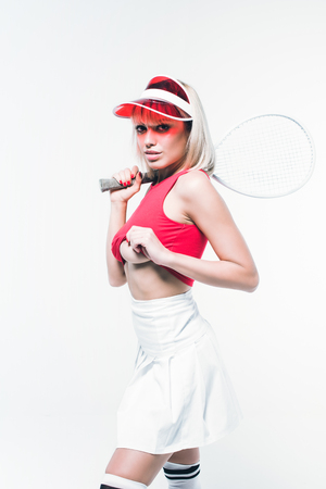 attractive young woman in sportswear with tennis racket looking at camera isolated on whiteの写真素材