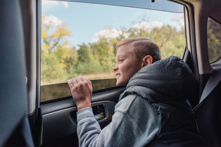 happy little boy looking through car windowの写真素材