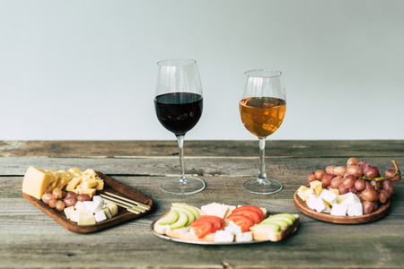 Two glasses of wine and food on a wooden table の写真素材