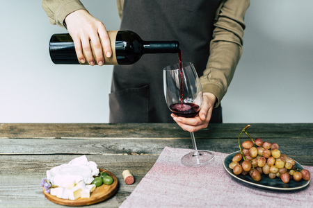 Female sommelier pouring red wine into glass の写真素材