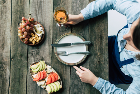 Top view of Female sommelier holding glass of white wine in a hand and sitting at the tableの写真素材