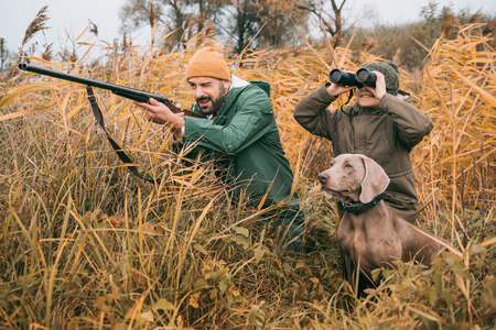 Father and son sitting in a bushes and hunting down an animal の写真素材