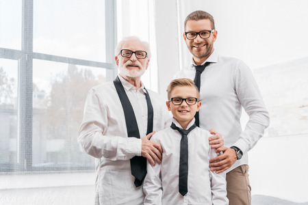 Father, son and grandfather wearing formal clothing, standing together and looking at cameraの写真素材