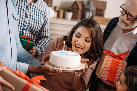 young woman biting birthday cake presented by cakeの写真素材