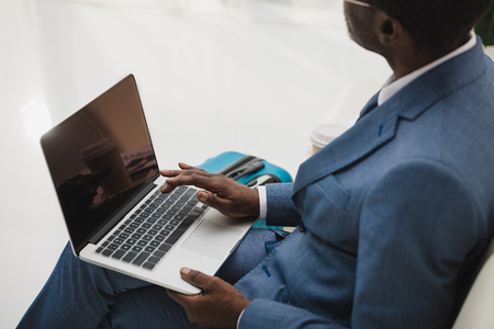 Cropped image of African american man working with a laptop while sitting at the airportの写真素材