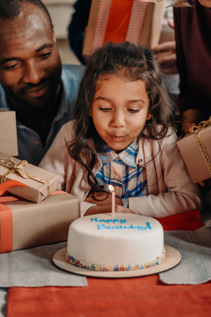 african american father and daughter blowing candle on birthday cakeの写真素材