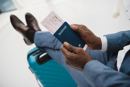 Cropped image of African american man holding passport and fly ticket in handsの写真素材