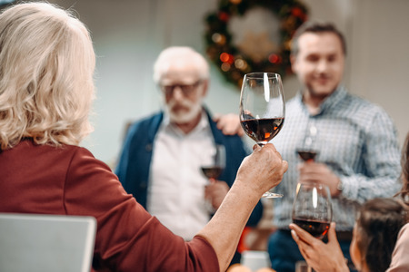 back view of woman making toast on christmas while celebrating with family
