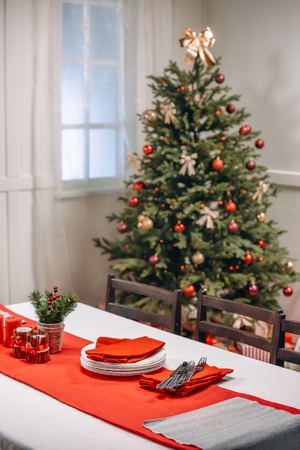 christmas table with tableware ready for serving in decorated living roomの写真素材