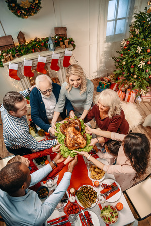 high angle view of happy large family holding christmas turkey togetherの写真素材